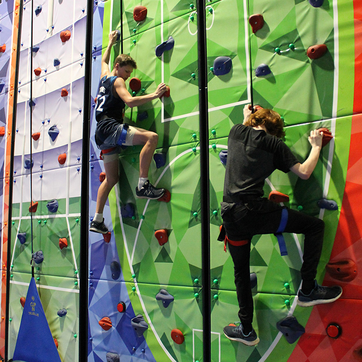 Two Life Camp participants climbing a green rock wall