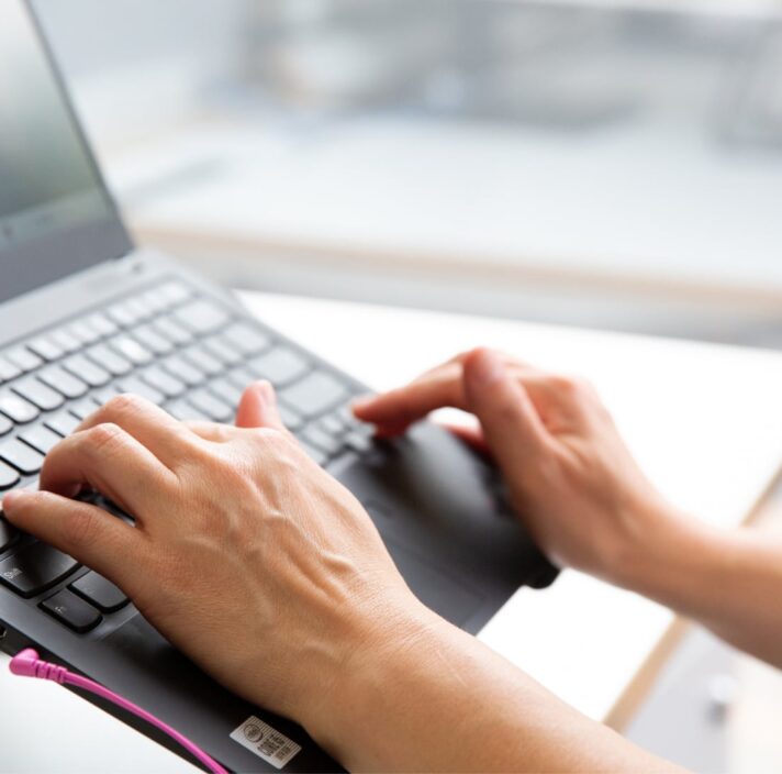 Person's hand using the keyboard of a laptop.