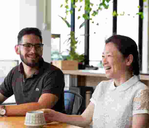Two people sitting at cafe table. Both people are smiling.