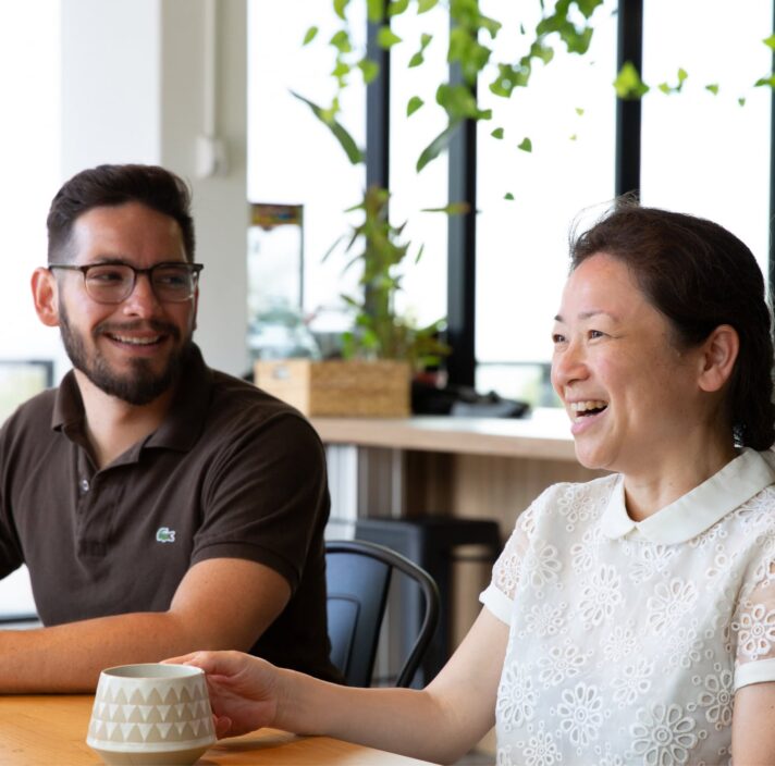 Two people sitting at cafe table. Both people are smiling.