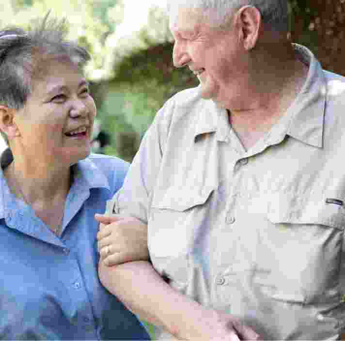 Two people outside looking at each other. One is holding the other at the elbow.