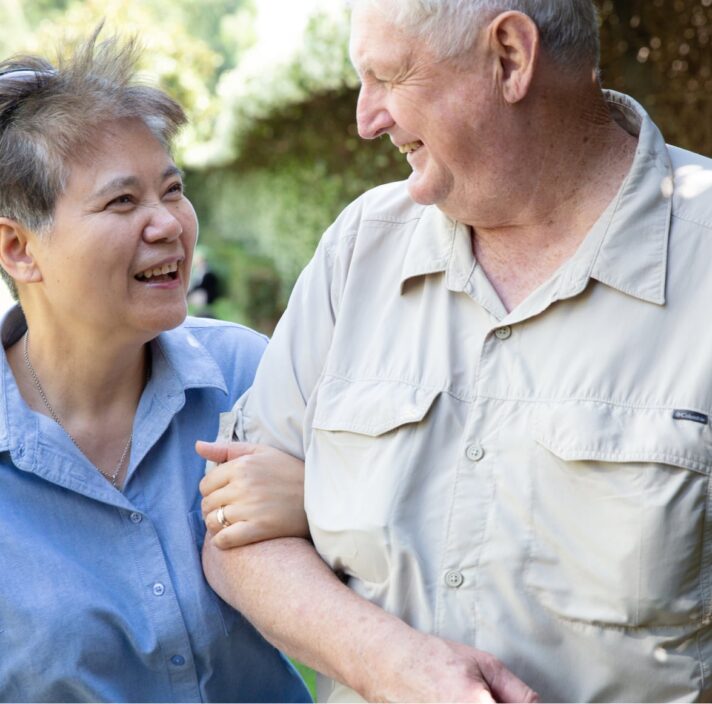 Two people outside looking at each other. One is holding the other at the elbow.