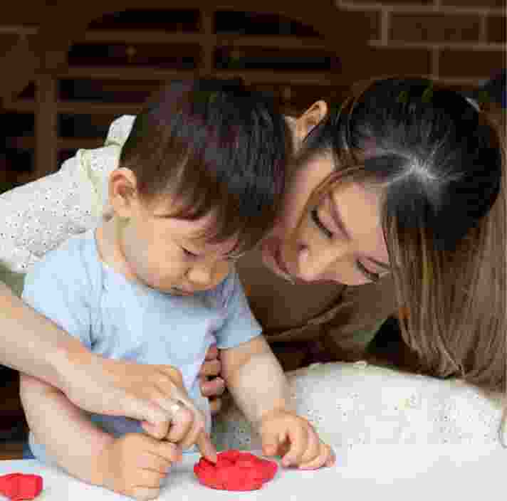 A mother helping her toddler play with play dough.