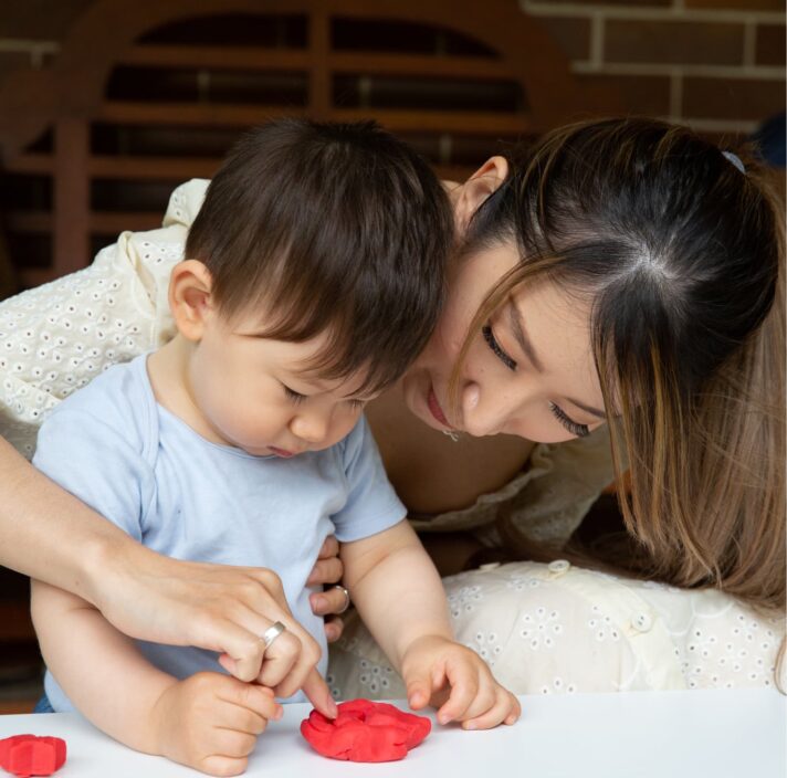 A mother helping her toddler play with play dough.
