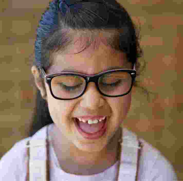 A child laughing who is looking down.