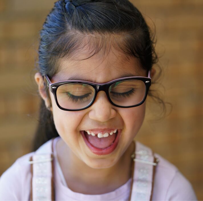 A child laughing who is looking down.