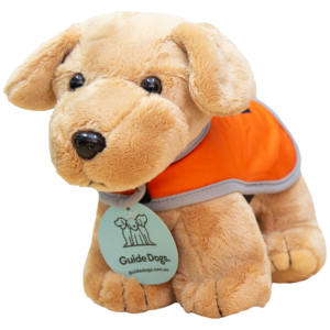 Plush toy guide dog wearing an orange vest and a tag labeled Guide Dogs.