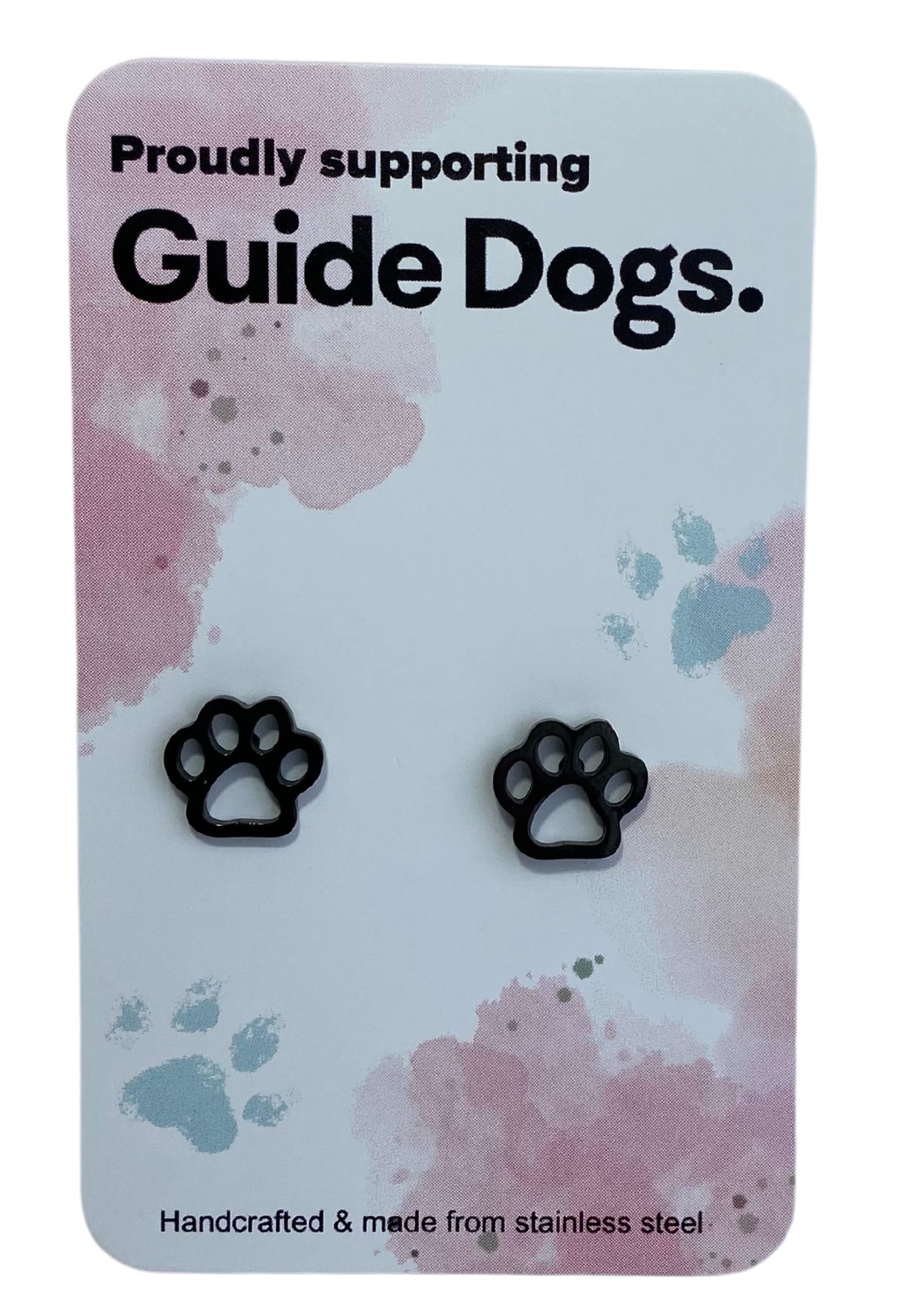 The image shows a black paw-shaped earring on a card that reads "Proudly supporting Guide Dogs." The card has a pastel background with pink and blue splotches and small paw print designs. At the bottom, it states, "Handcrafted & made from stainless steel."