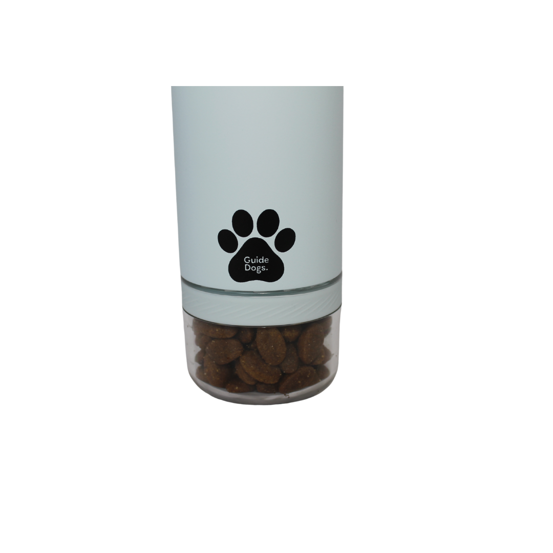 Image shows light blue container with a black paw print logo labeled “Guide Dogs,” with brown kibble inside a clear bottom compartment.