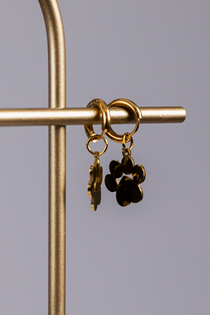 The Earrings - Huggie Paws are gold hoop earrings with black paw print charms, displayed on a gold metal stand against a plain background.