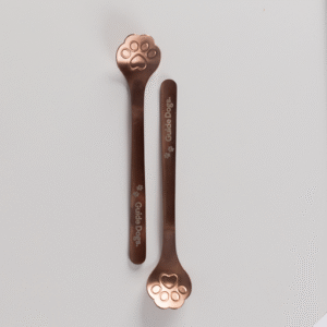 Two Spoon - Paw Print metallic stirrers with paw-shaped ends and Guide Dogs text are placed parallel on a plain white background.