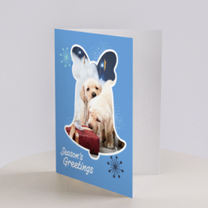 A blue Christmas Cards - Puppies design featuring two yellow Labrador puppies, holiday decorations, and Seasons Greetings on the front.