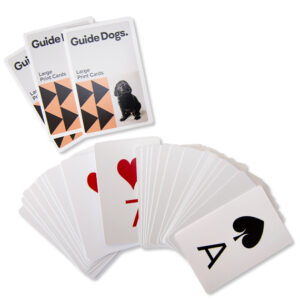 Playing Cards with a Guide Dogs design, featuring large print for easy reading. Cards are shown spread out with red and black suits and an ace of spades.