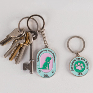 A set of keys with the Keyring and Charm Set featuring a professional dog treat dispenser keychain and a separate "Just here for the treats" charm with a paw print.