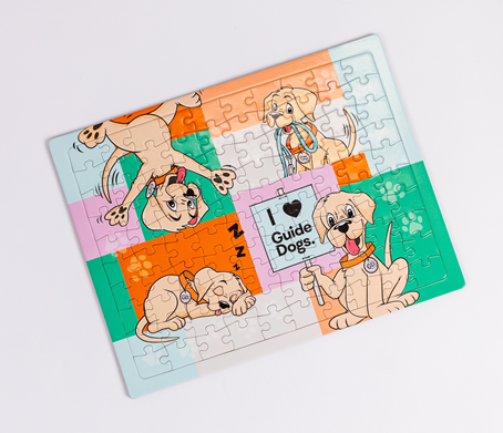 A completed Jigsaw Puzzle features cartoon guide dogs, one holding an I love Guide Dogs sign, set against a background of colorful blocks.