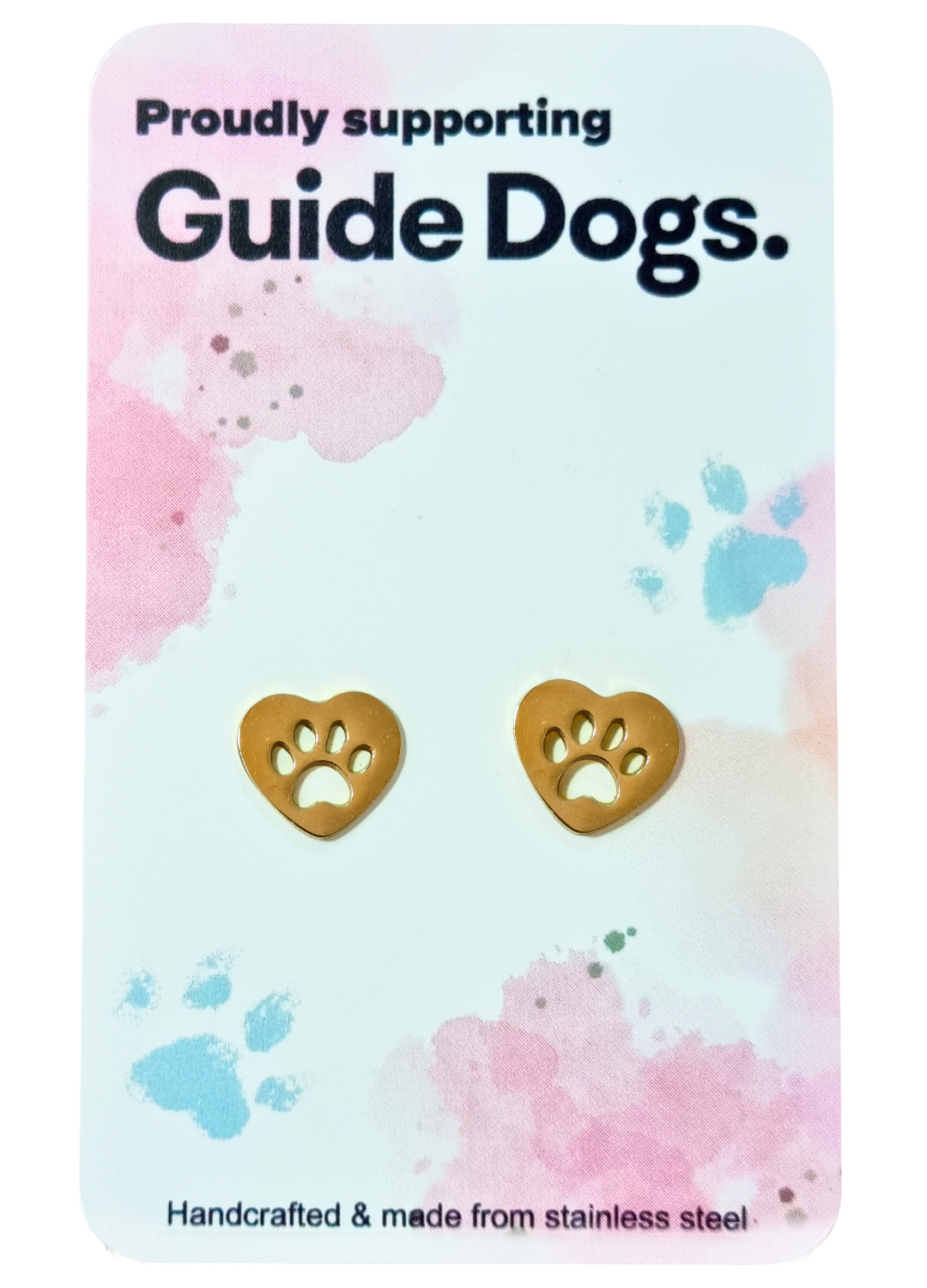 Earrings - Heart: Gold heart-shaped stud earrings with paw print cutouts, displayed on a card with pastel paw prints and the message "Proudly supporting Guide Dogs.