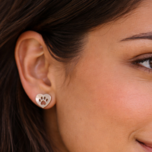 Close-up of a woman's ear wearing Earrings - Heart featuring a paw print design.