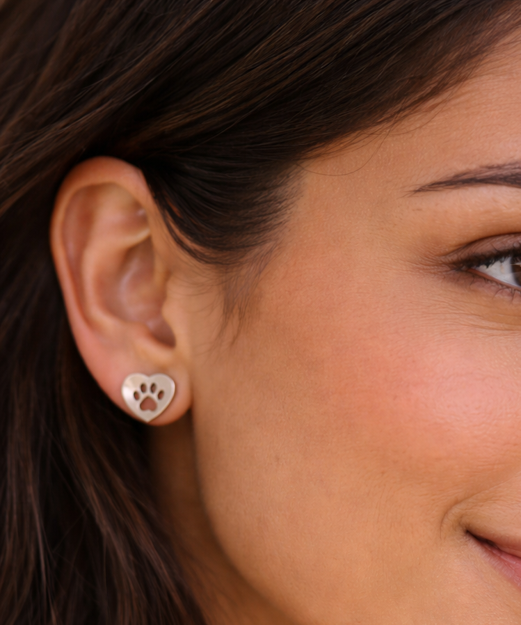 Close-up of a woman's ear wearing Earrings - Heart featuring a paw print design.